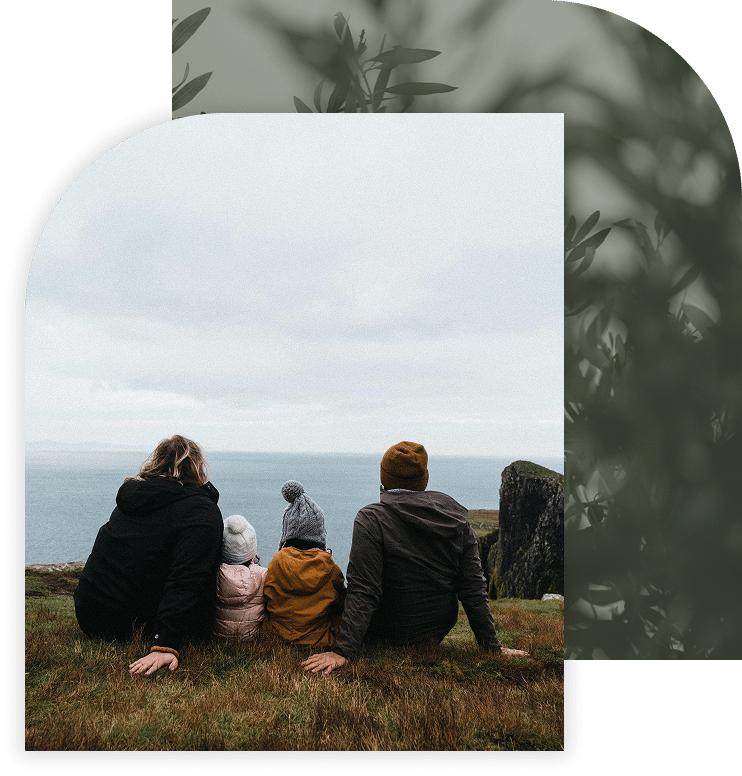 Family sitting on a grassy cliffside, looking out over the ocean.