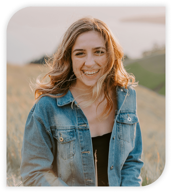 Cheerful woman standing in a grassy field.