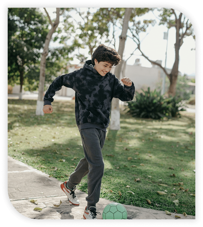 Smiling boy playing soccer in a park.