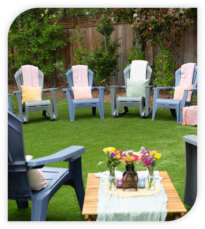 Outdoor circle of blue chairs with pillows and flowers on a lawn table.