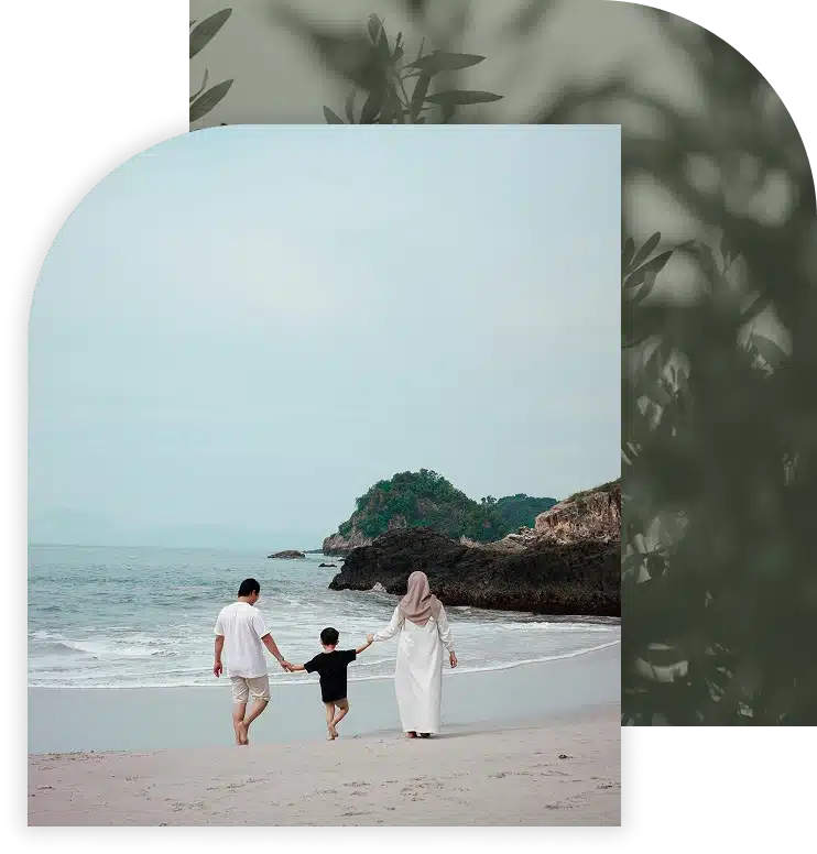 A family walks on a sandy beach.