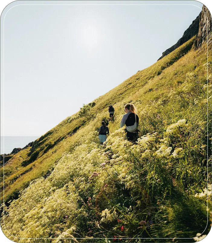 A group of people hike up a steep hillside.